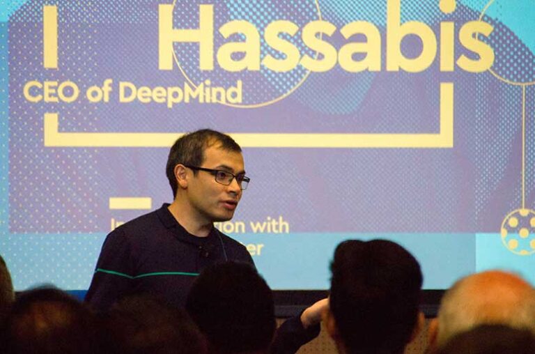 Demis Hassabis speaking at a conference in front of a public